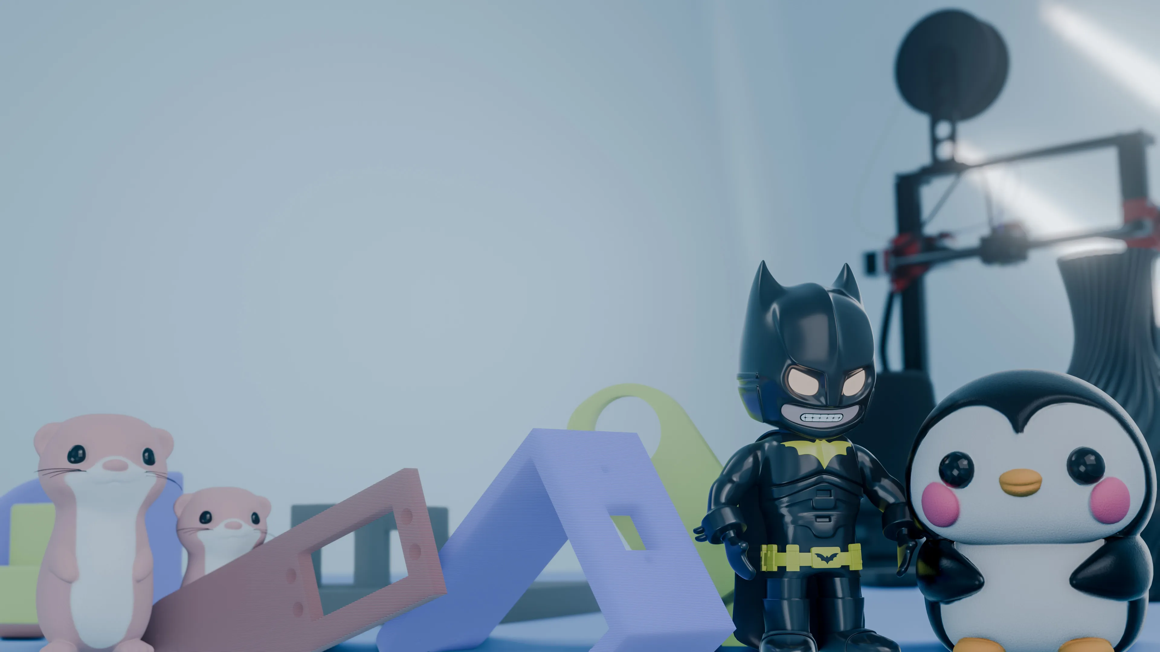 Printed figurines: a Batman figure and a penguin on a desk next to a 3D printer